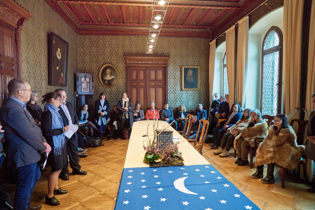 Zeremonie im Rathaus, mehrere Personen sitzen bzw. stehen um einen langen Tisch