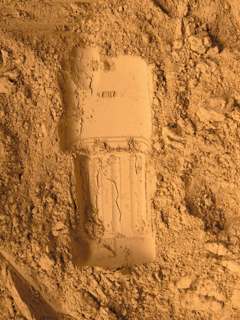 Abdruck eines Handys im Sand