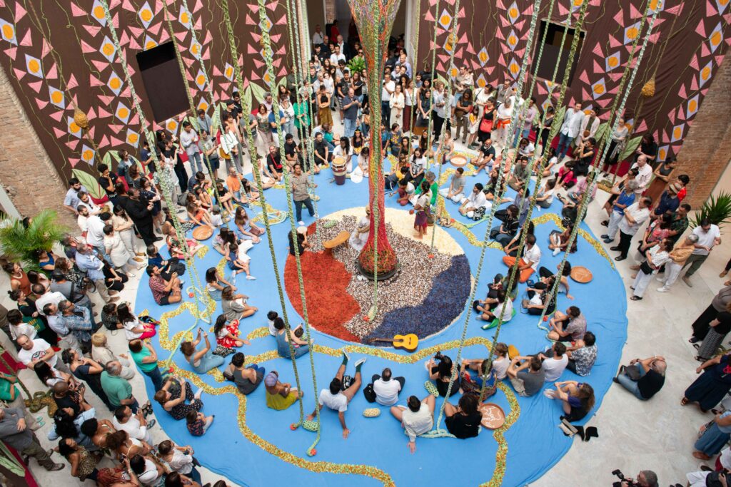 Kunstinstallation, dazwischen Menschen, die auf dem Boden sitzen